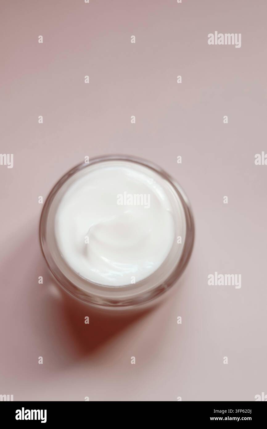 Crema per la cura della pelle in un barattolo di vetro aperto, che mostra una texture bianca e ricca. Prodotto di bellezza per il trattamento cosmetico Foto Stock