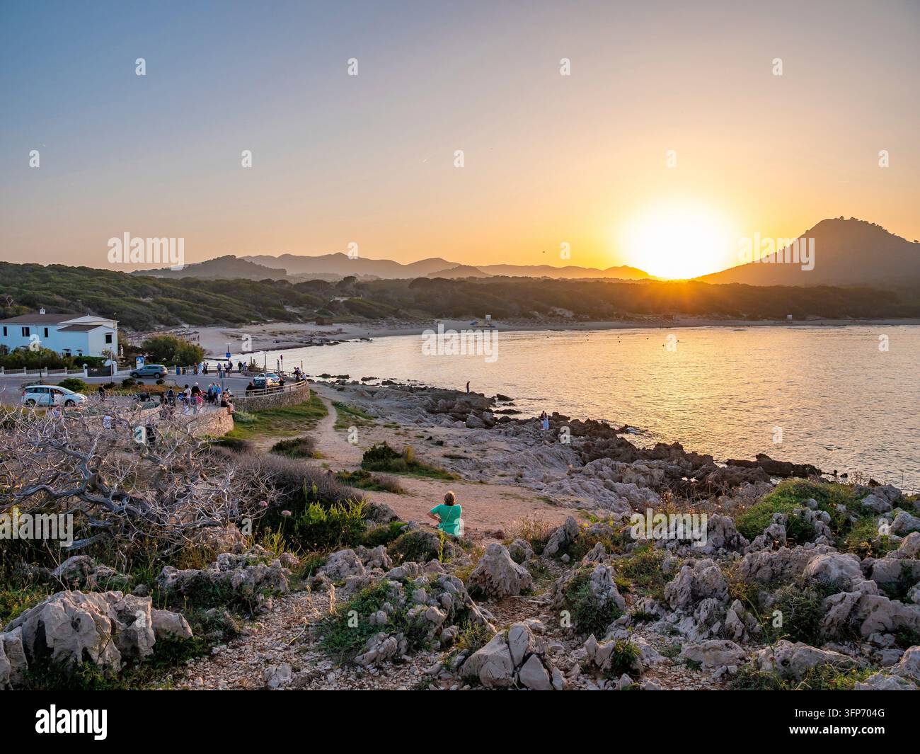 Un drammatico tramonto dorato illumina la costa rocciosa e le acque tranquille della baia di Cala Rajada sulla costa orientale di Maiorca, mettendo in mostra il Mediterraneo Foto Stock