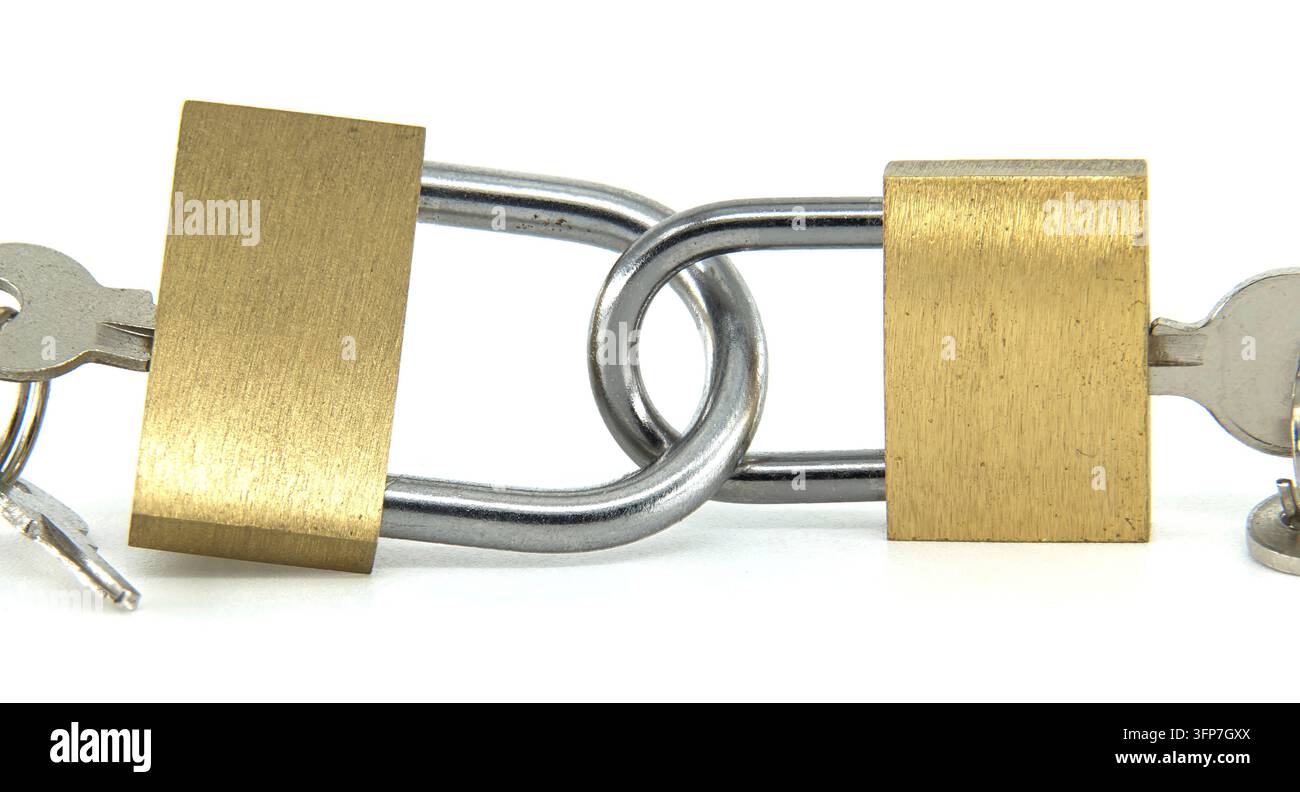 Due serrature di ottone sono saldamente interconnesse attraverso i loro catenacci, con chiavi inserite, rappresentando una forte sicurezza e interconnessione Foto Stock