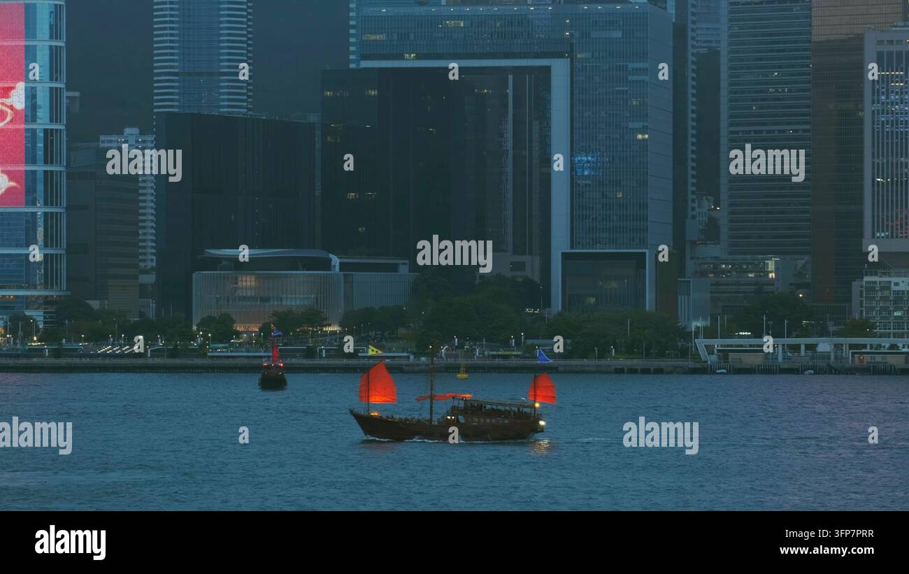 Junk tradizionale cinese con vele rosse nel Victoria Harbour di notte, Hong Kong Foto Stock