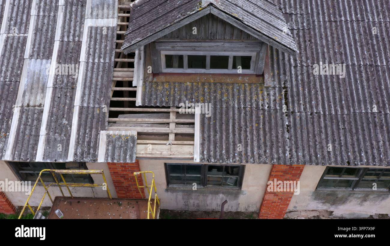 Vista aerea di un tetto di edificio in fase di ristrutturazione con travi di legno a vista, pannelli ondulati, una finestra a mansarda e un'impalcatura gialla visibile sotto Foto Stock
