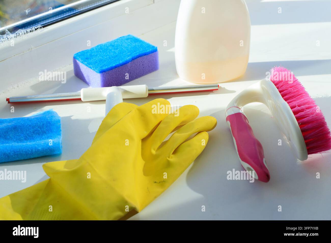 Set di attrezzature per la pulizia delle finestre con guanto per spolverare, spugna e flacone spray sul davanzale come concetto. Forniture per l'igiene domestica e strumenti detergenti per il vetro di casa Foto Stock