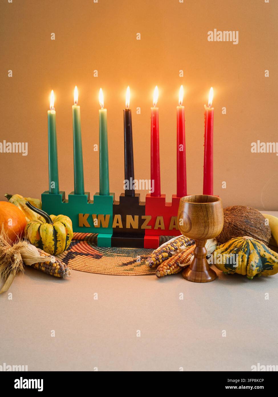Kinara Kwanzaa con sette candele accese circondate da frutti tradizionali delle feste Foto Stock