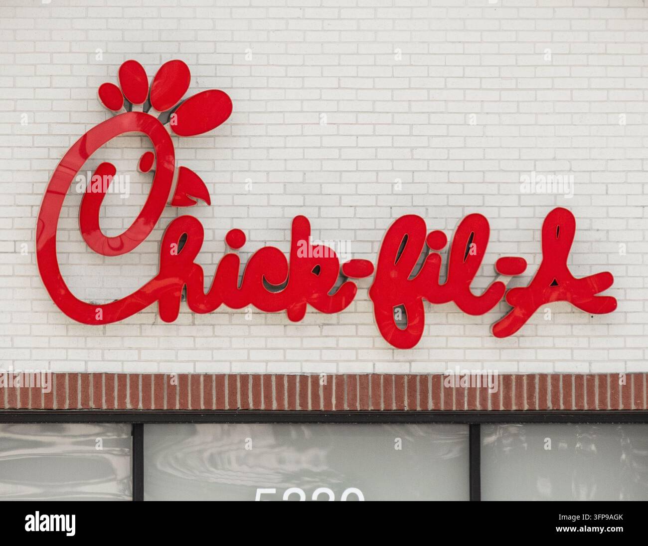 19 aprile 2026, Primo piano del logo rosso del ristorante di fast-food Chick-fil-A montato su una facciata in mattoni bianchi sopra una cornice in mattoni a Sarasota, Florida. Foto Stock