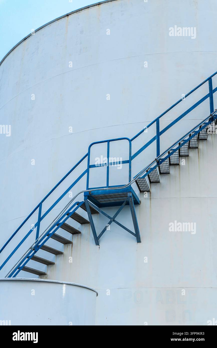Scala in metallo blu sulla parte esterna di un serbatoio di stoccaggio industriale bianco Foto Stock