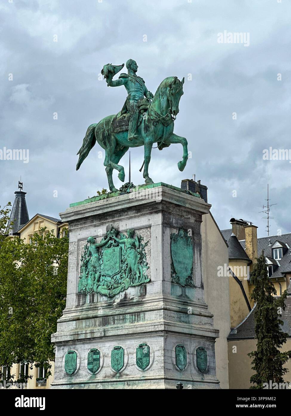 Statua equestre in bronzo di un monarca su un piedistallo in pietra ornato contro un cielo nuvoloso. Statua equestre maestosa in bronzo di un sovrano storico su un decorato - Immagine stock catturata con smartphone