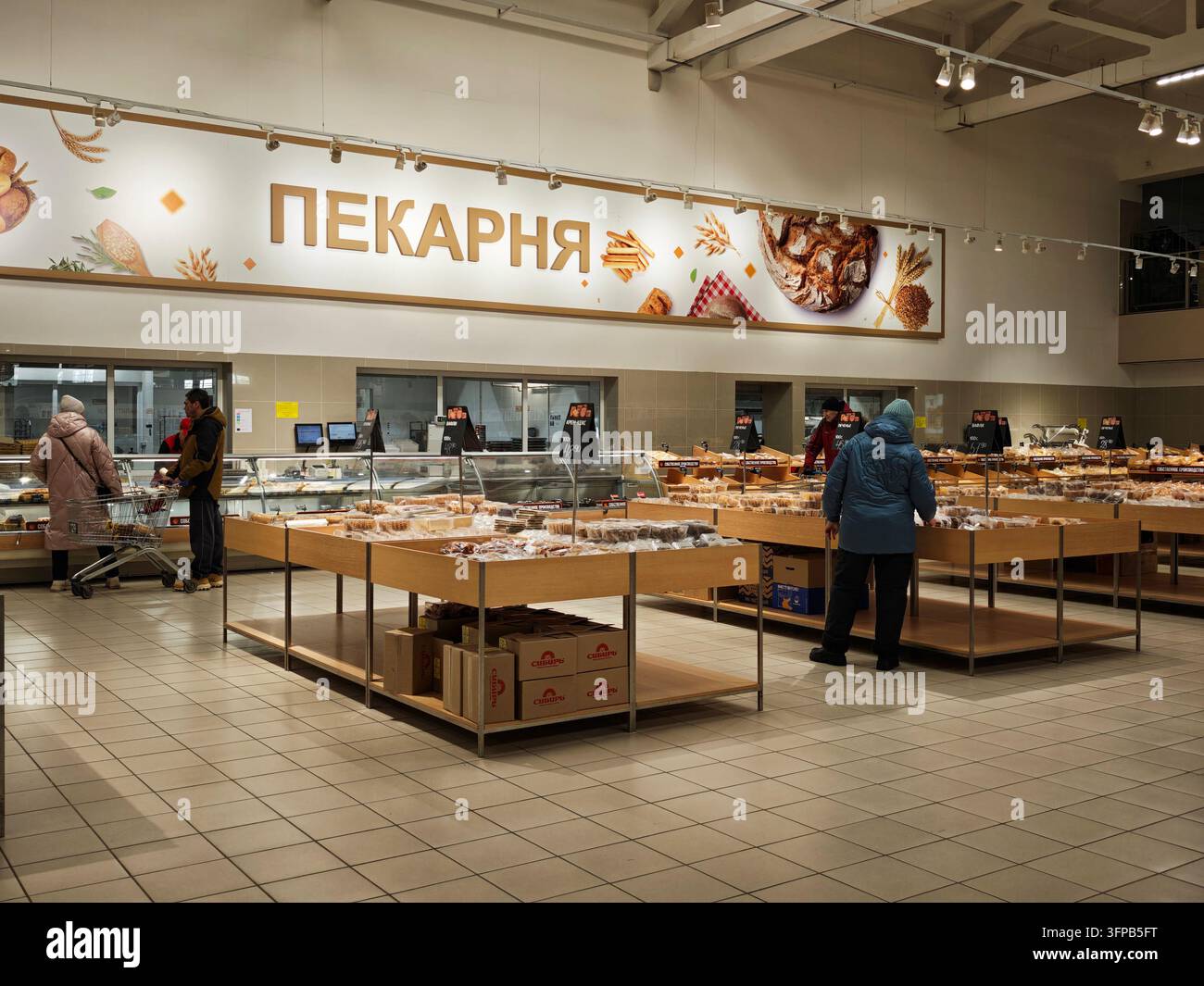 Kirov, Russia – 8 febbraio 2026: I clienti sfogliano vari prodotti da forno e scelgono articoli da acquistare in un affollato reparto di panetteria. Foto Stock