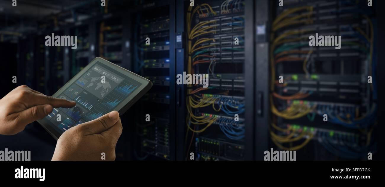 Uomo o tecnico che utilizza un dashboard su tablet accanto ai rack di rete e server, monitorando i sistemi di rete e gestendo l'infrastruttura IT del data center. Foto Stock