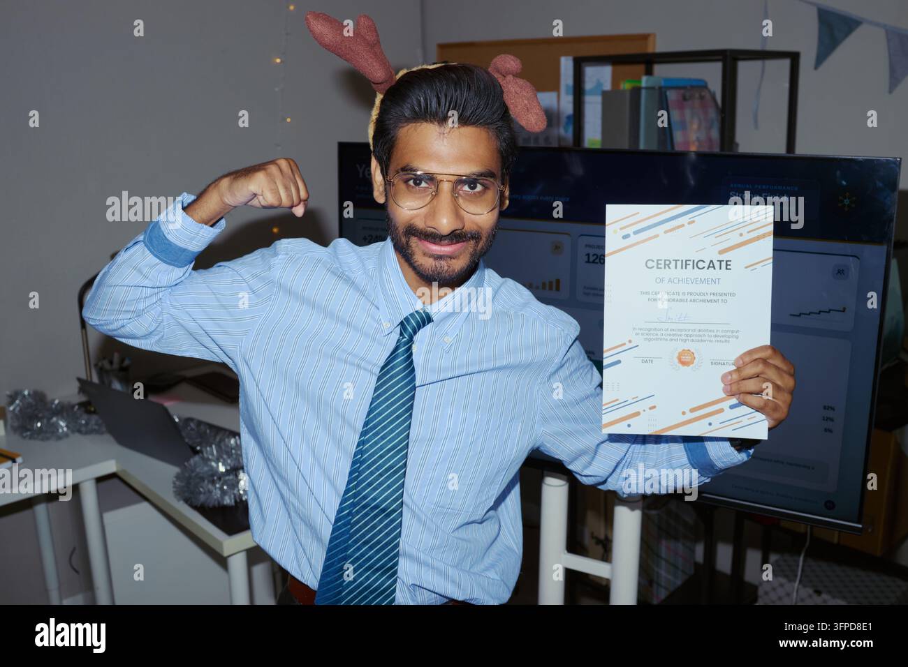 Ritratto di un uomo indiano che tiene un certificato in ufficio a Natale Foto Stock