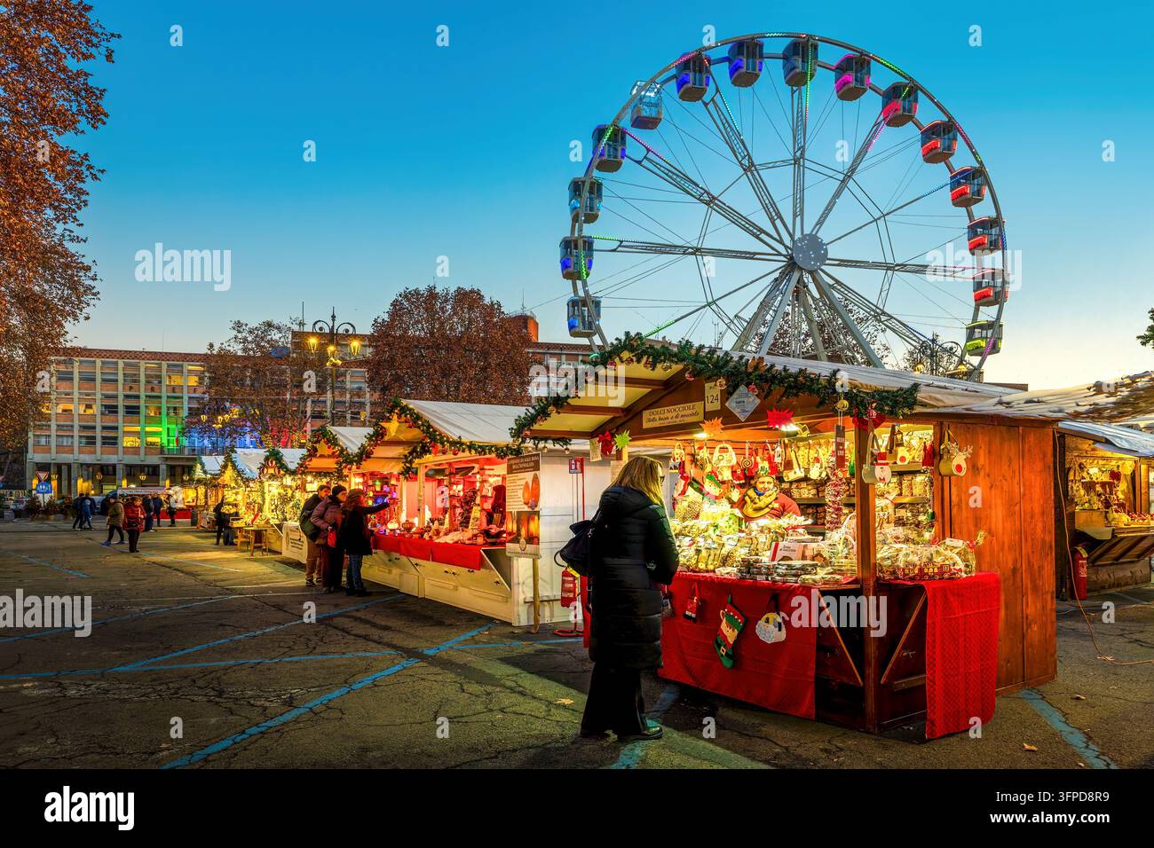 Giostra e bancarelle di legno illuminate al mercato di Natale ad Asti, Italia. Foto Stock