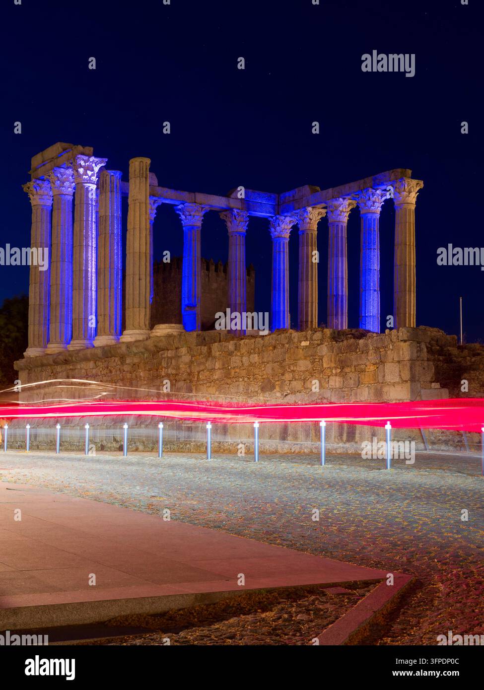 Tempio romano di Diana illuminato di notte con scie di luci delle auto, Évora, Portogallo Foto Stock