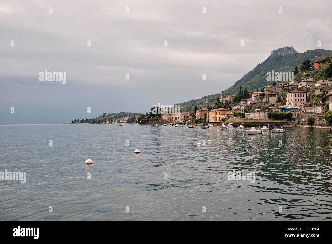 Gargnano sul lago di Garda. La riva occidentale del lago di Garda; le barche sono ancorate; il tempo è mutevole, una giornata estiva leggermente nuvolosa. Foto Stock
