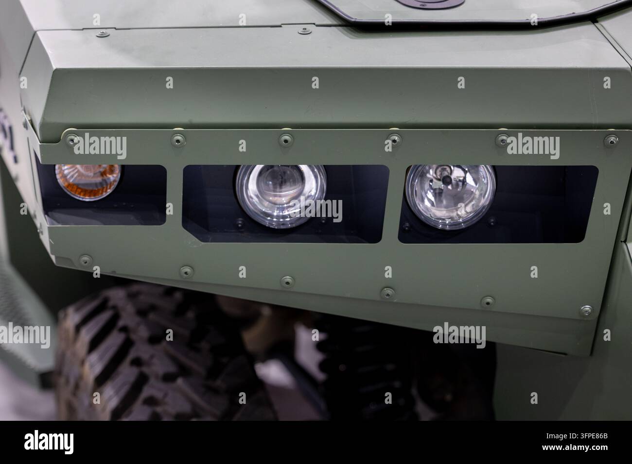 I fari anteriori e gli indicatori di direzione di un veicolo militare sono inseriti in una carrozzeria del paraurti in metallo blindato. Un robusto camion tattico dell'esercito mostra lampade in vetro rotonde. Foto Stock