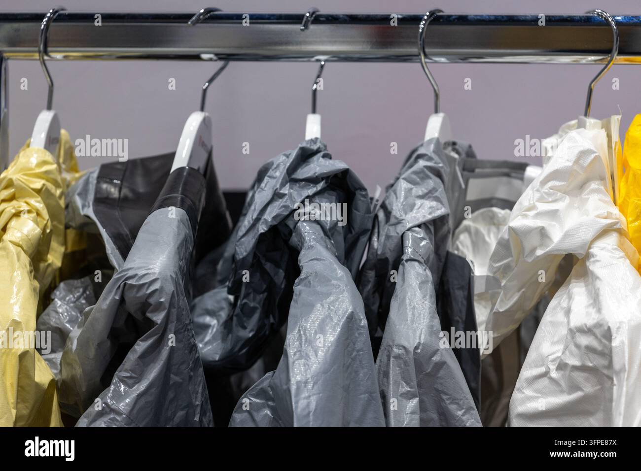 Abbigliamento protettivo e tute di sicurezza appese a supporti metallici all'interno dello spazio di stoccaggio. Abbigliamento da lavoro impermeabile per materiali pericolosi. Foto Stock