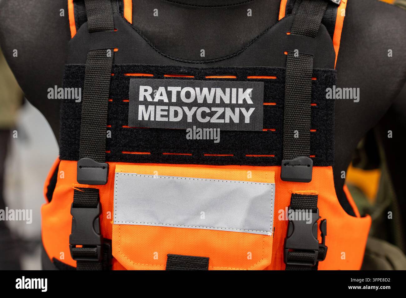 Giacca tattica paramedica mostra una toppa di identificazione "Ratownik Medyczny" su un supporto per armatura arancione e nera. Foto Stock