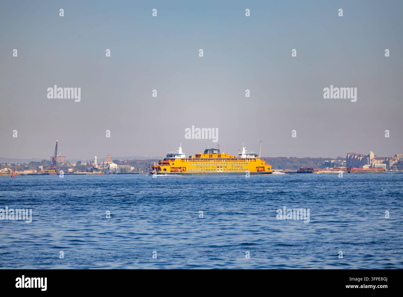 New York, USA - 20 settembre 2026: L'iconica barca passeggeri arancione della Staten Island Ferry che naviga sulle acque blu del porto di New York in una giornata di sole Foto Stock