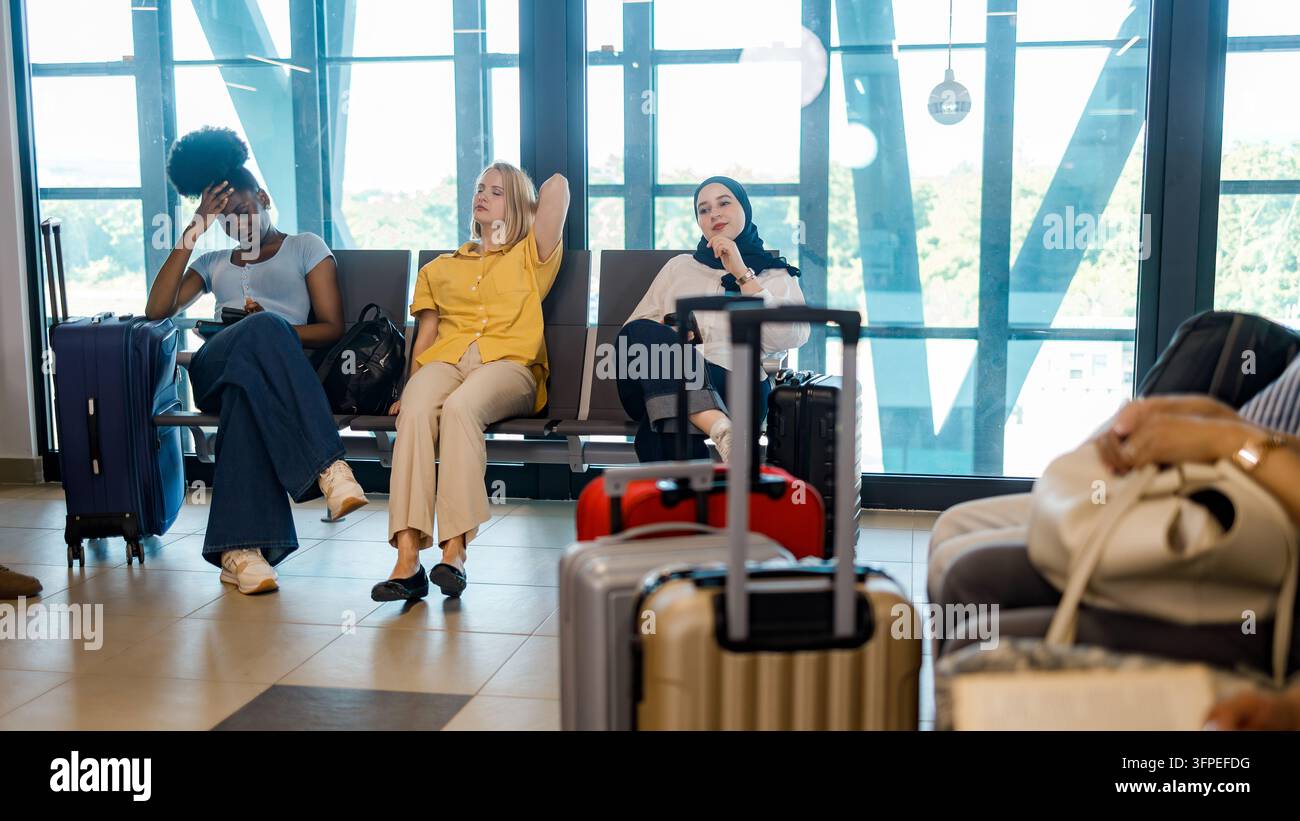 Le persone sono sedute in una sala d'aspetto dell'aeroporto in attesa dei loro voli con il bagaglio accanto. Foto Stock
