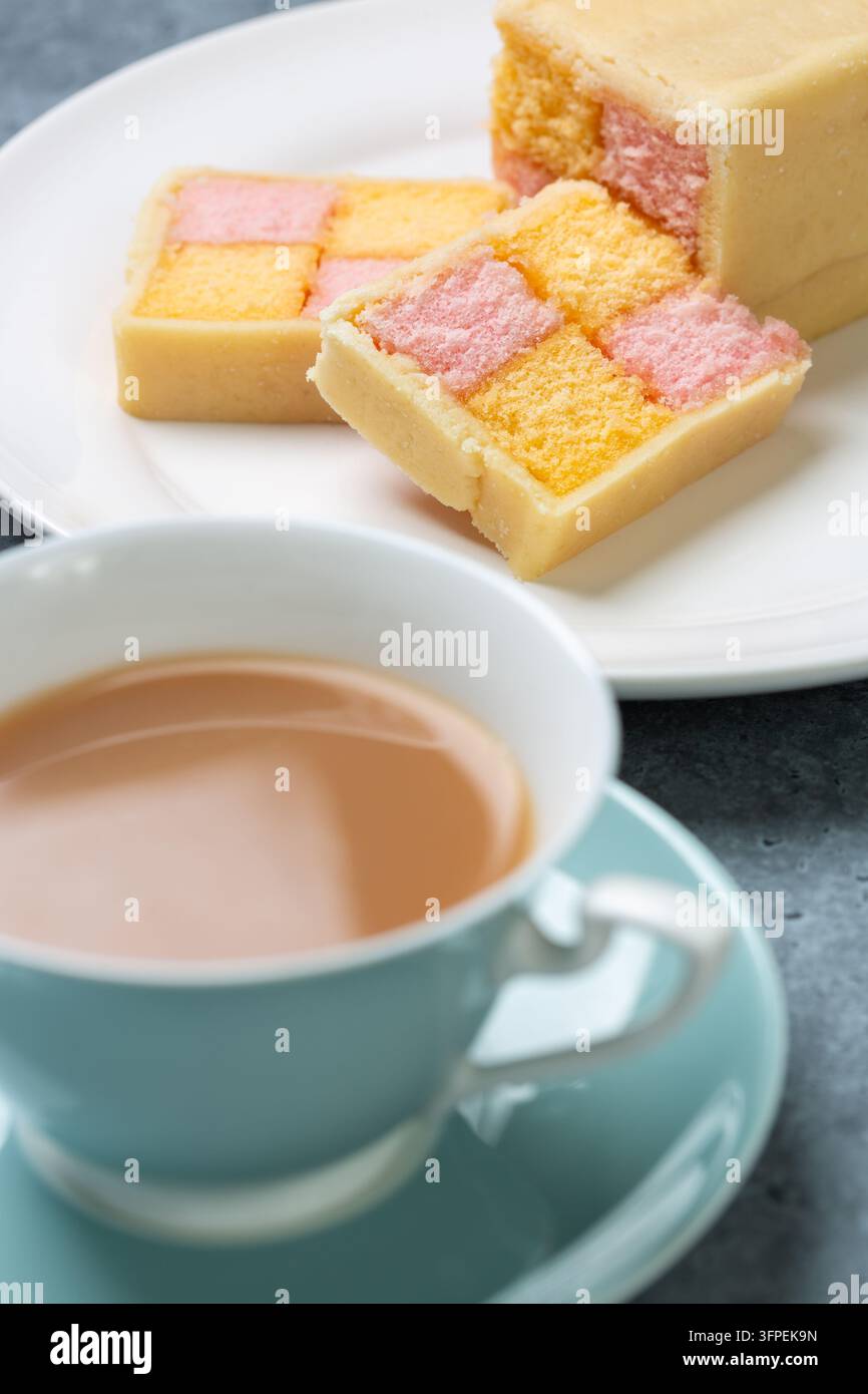Fetta di torta Battenberg – una tradizionale torta marziana britannica con quadrati rosa e gialli e una tazza di tè Foto Stock