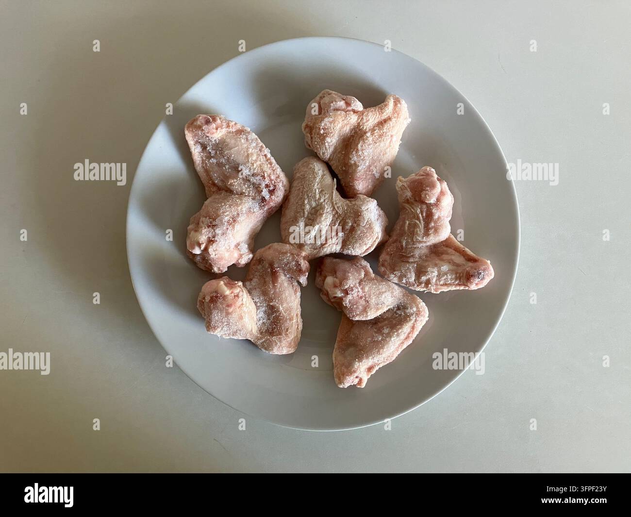 Prima vista di sei ali di pollo crude su piatto bianco Foto Stock