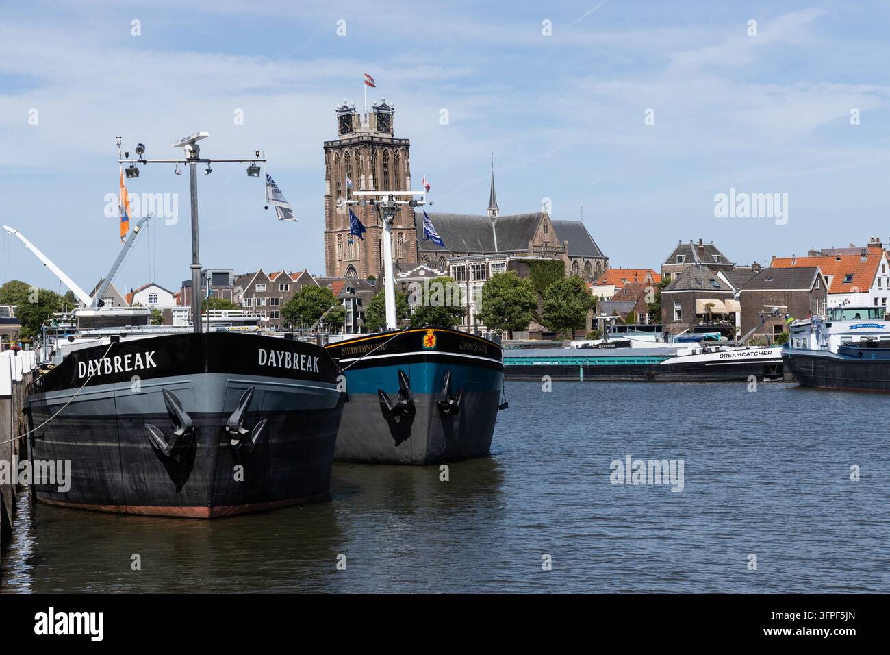 Chiatte nel porto dominate dalla maestosa Grande Chiesa. La Grote Kerk Dordrecht Paesi Bassi Foto Stock
