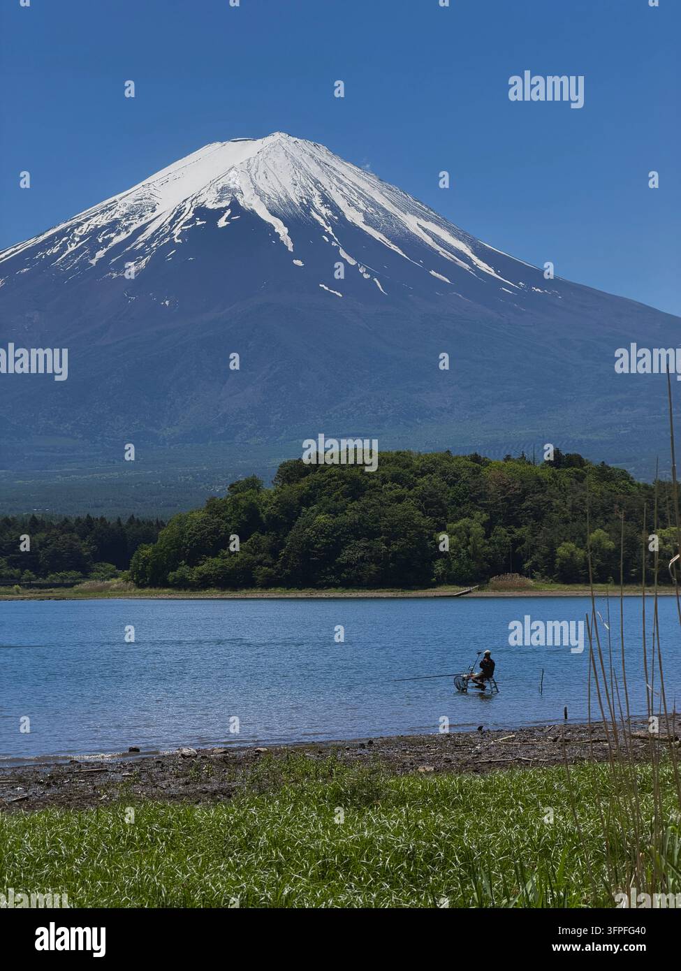 Monte Fuji che sovrasta un lago con un pescatore solitario in Giappone in una limpida giornata di primavera - Immagine stock catturata con smartphone