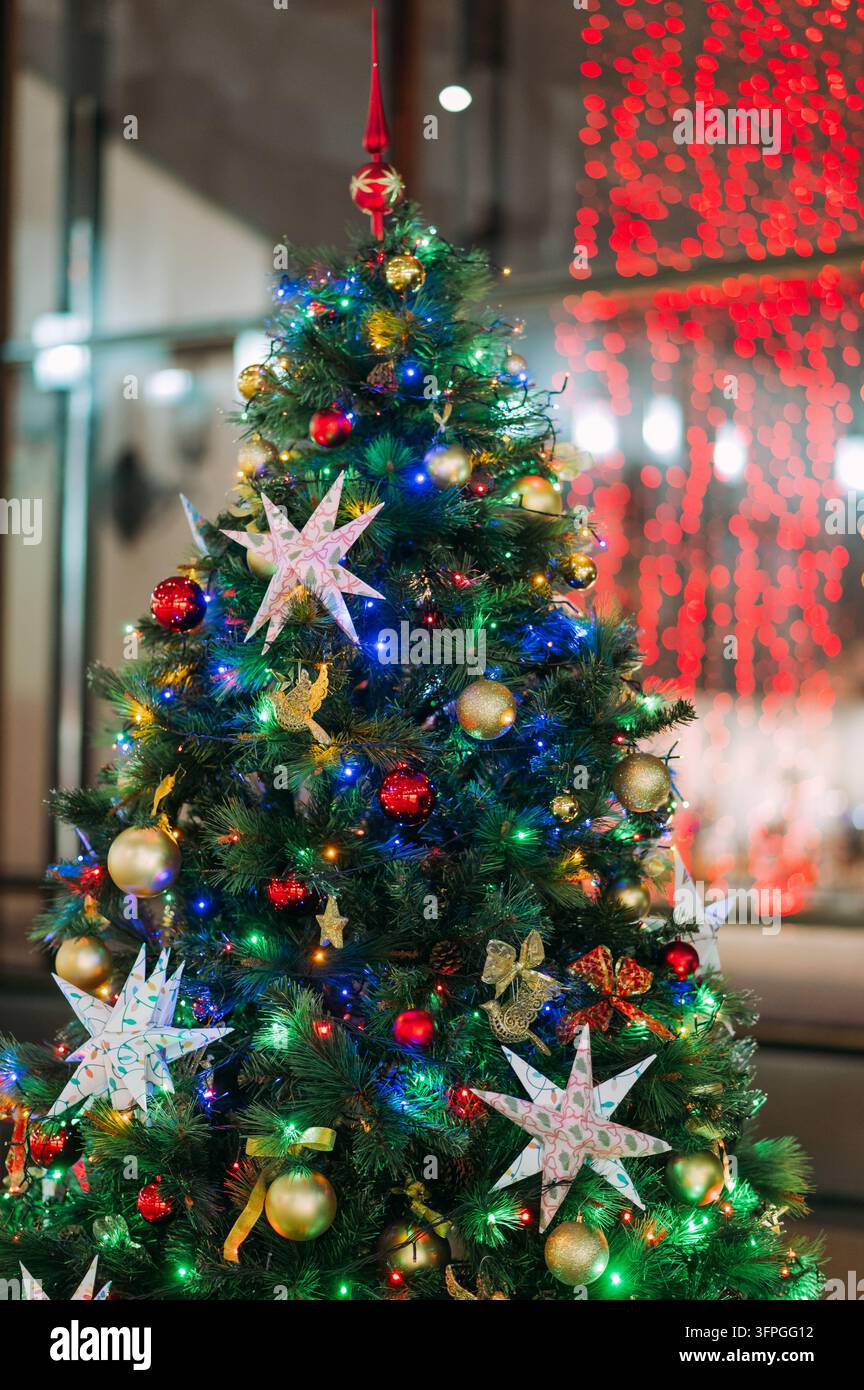 Albero di Natale decorato con luci colorate e ornamenti in un ambientazione festiva al chiuso Foto Stock