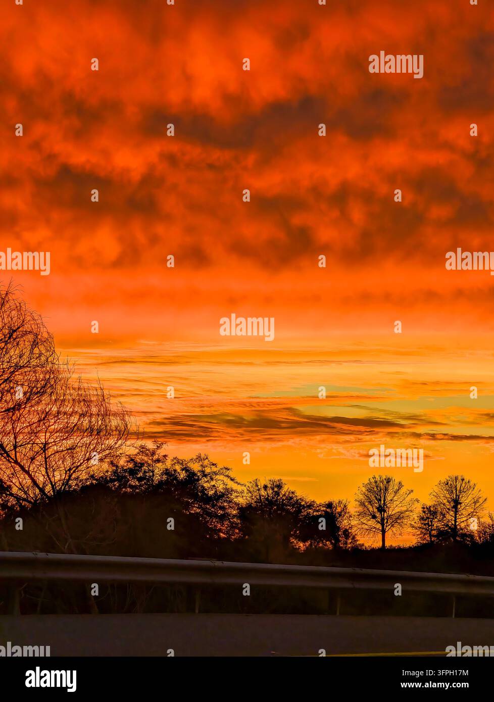 Trascinante tramonto luminoso che tinge le nuvole di sfumature di arancione, rosa e nero Foto Stock