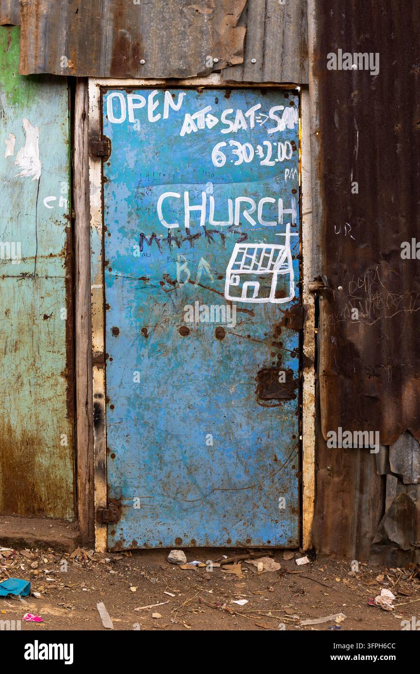 Porta metallica dipinta di blu dell'ingresso di una chiesa con orari di apertura scritti a mano in bianco e un disegno di una chiesa tra pareti di lamiera ondulata arrugginita nel Foto Stock