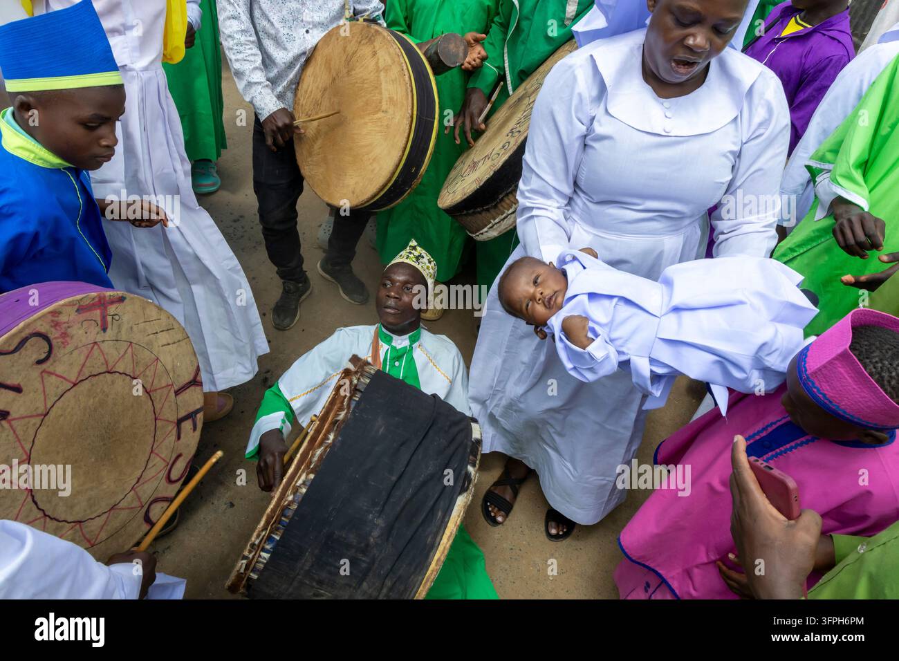 Tamburi con grandi tamburi a mano e una donna che tiene un bambino durante una processione battesimale a Kibera, Contea di Nairobi, Nairobi, Kenya Foto Stock