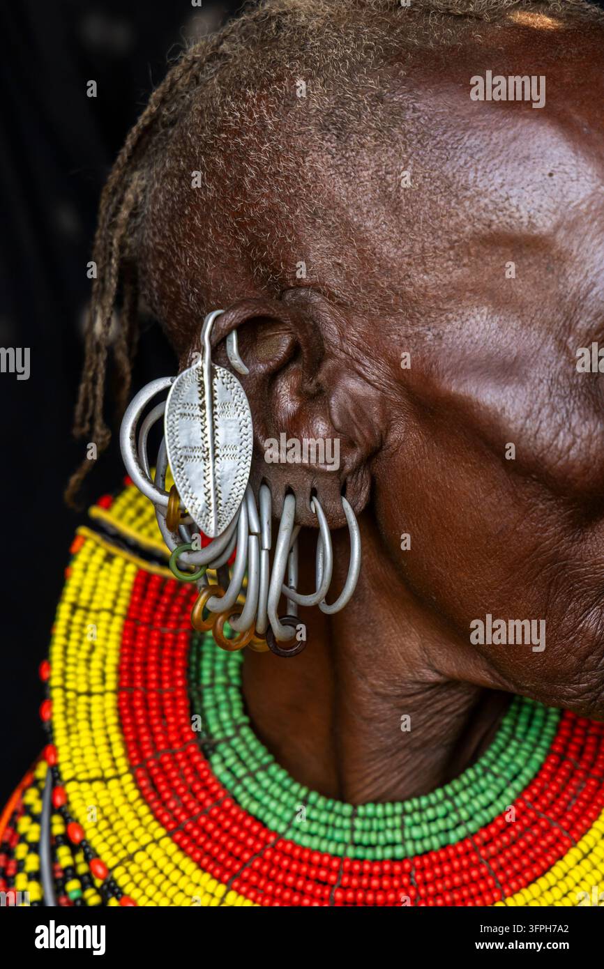 Primo piano del profilo di una donna anziana della tribù Turkana che mostra un orecchino a foglia d'argento e anelli di metallo appesi all'orecchio, Contea di Marsabit, Loiyangalani Foto Stock