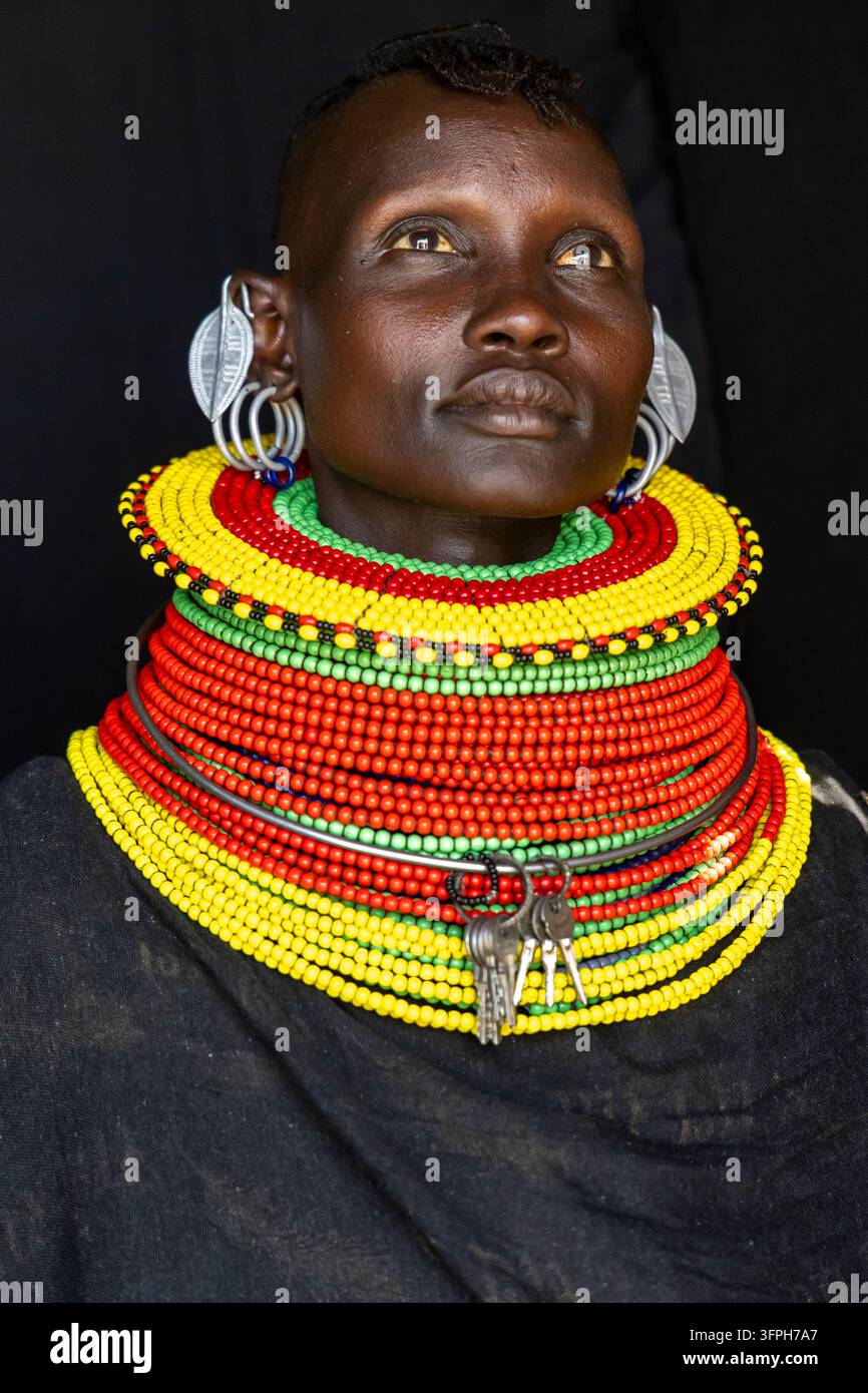Ritratto di una donna della tribù Turkana che guarda verso l'alto con orecchini in foglia d'argento, spesse collane di perle e chiavi appese a un anello cervical, Contea di Marsabit, Loiy Foto Stock