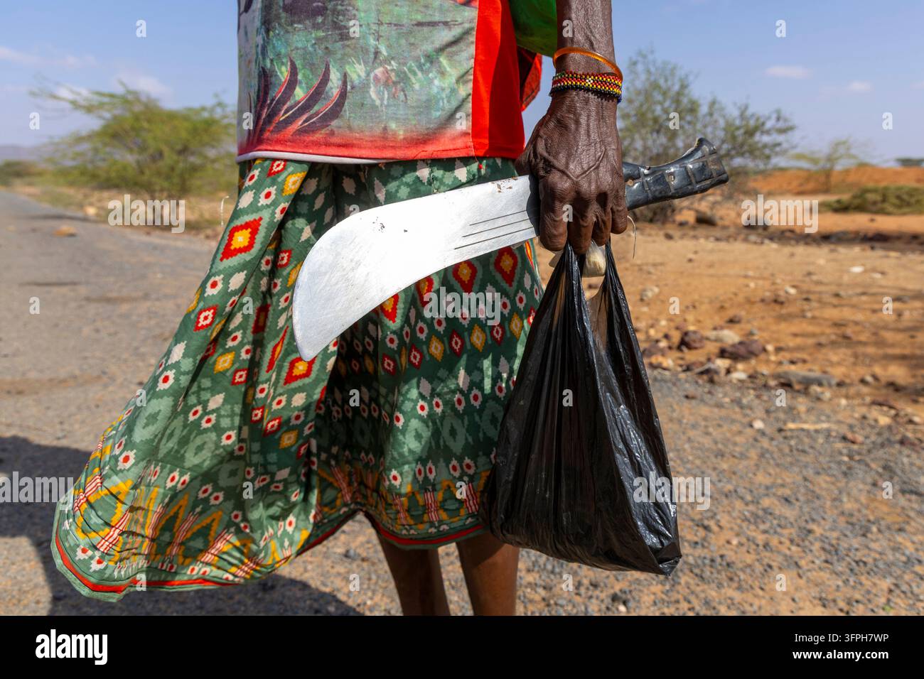 Primo piano della mano di un anziano della tribù Samburu che tiene una machete e un sacchetto di plastica nero, Samburu County, Samburu, Kenya Foto Stock