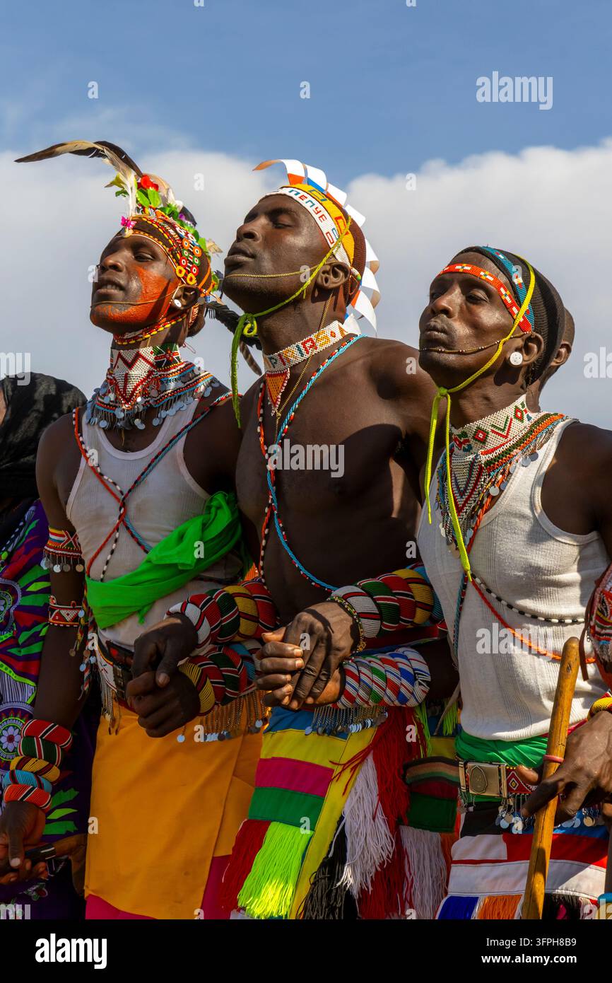 Tre uomini della tribù Rendille che danzano bracciato con gli occhi chiusi al Festival Culturale del Lago Turkana con collane di perle, diademi di piume e colorati ki Foto Stock