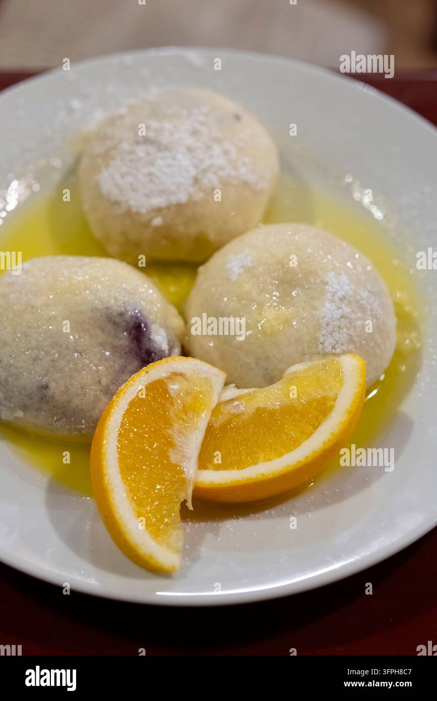 Gnocchi di frutta dolci con burro fuso, zucchero a velo e fette di arancia Foto Stock