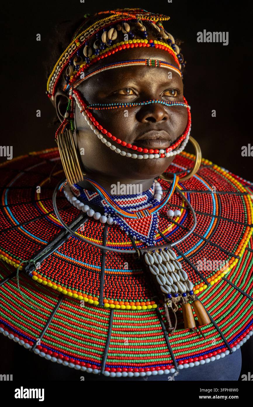 Ritratto di una donna della tribù Pokot che guarda di lato indossando un grande collare di perline con pendente a conchiglia e orecchini di ottone, Contea di Baringo, Churo Foto Stock