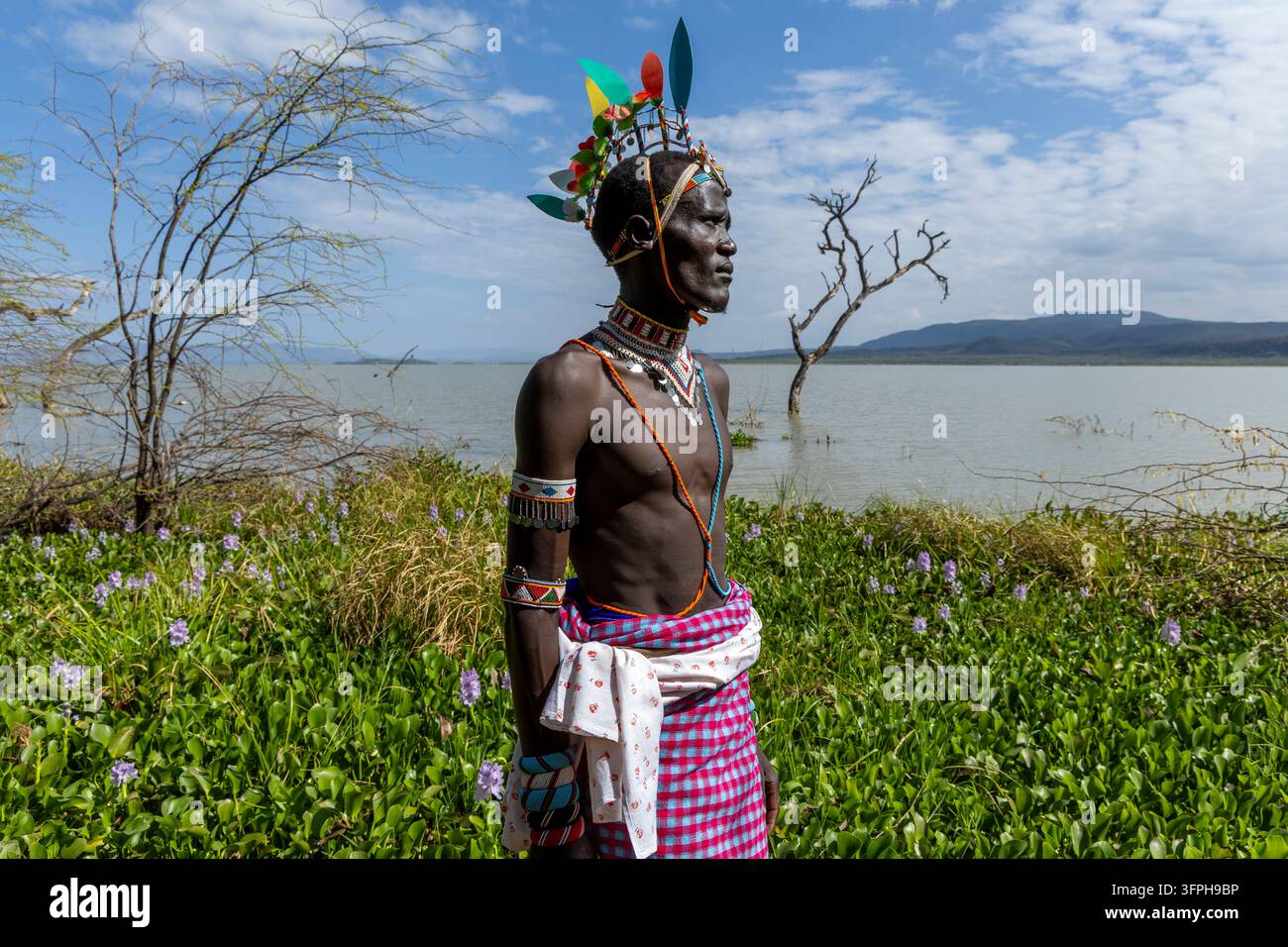 Due donne della tribù Njemps in abiti rossi e collane di perle sedute e che conversano sotto un albero con galline accanto a una capanna, Lago Baringo, Kenya Foto Stock