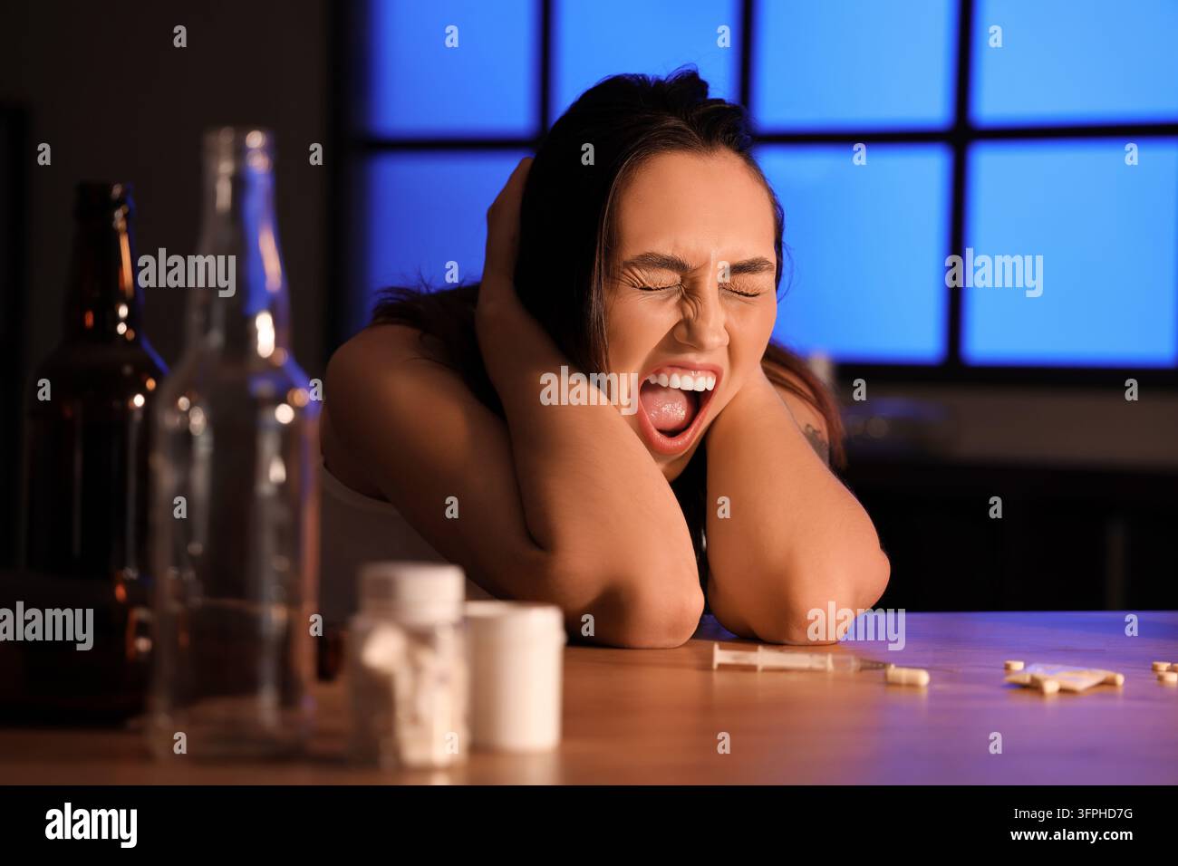 Crisi della salute mentale e dipendenza, donna che urla nella disperazione con alcol e droghe sul tavolo, abuso di sostanze e crollo emotivo Foto Stock