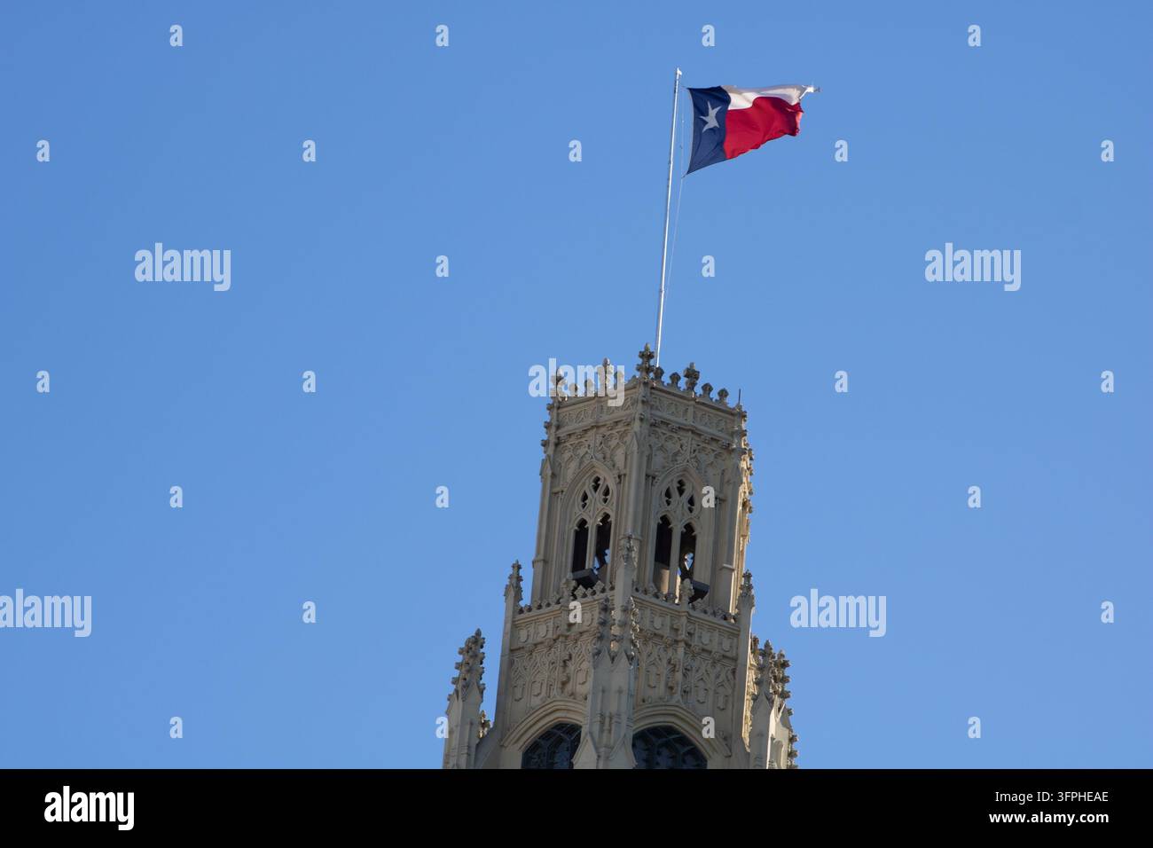 San Antonio, Texas, USA - Marzo 2025: Bandiera del Texas spiegata sopra la torre neogotica ornata dell'Emily Morgan Hotel. Foto Stock