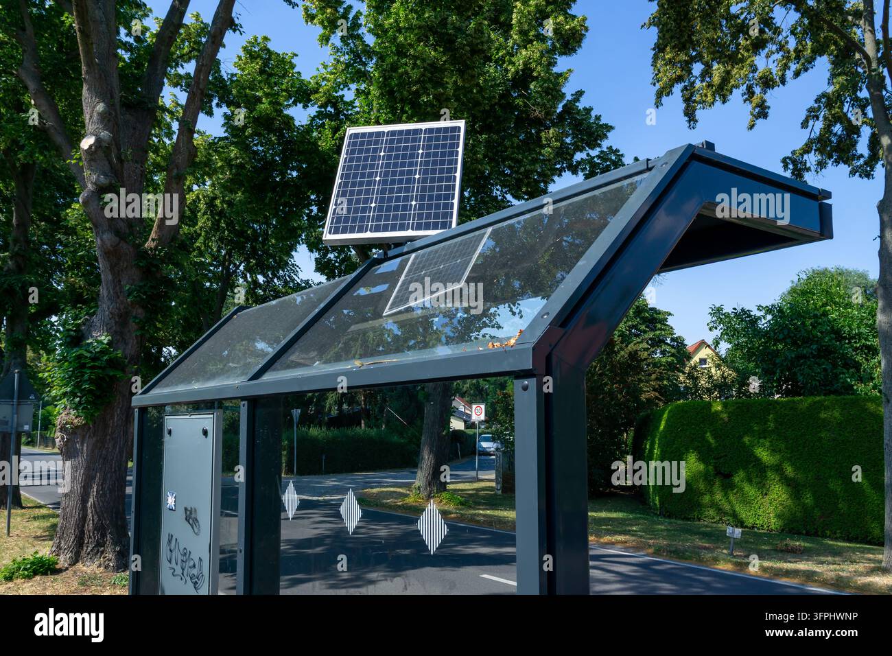 Un pannello fotovoltaico montato sopra il tetto in vetro di una fermata dell'autobus in un contesto residenziale nel Brandeburgo, Germania. Foto Stock