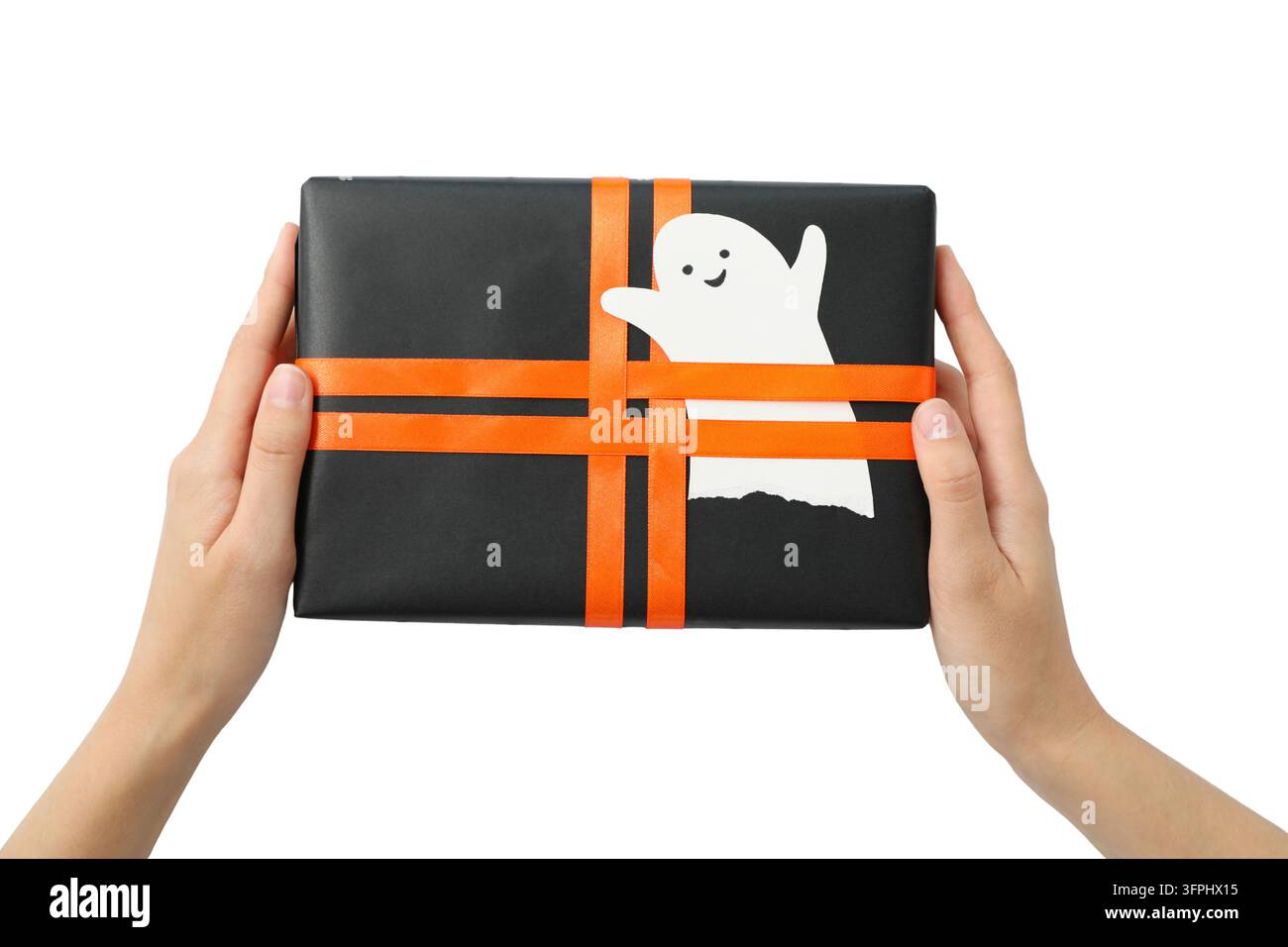 Regalo di Halloween. Mani che tengono un regalo incartato con nastri arancioni e motivo fantasma, isolato su sfondo bianco. Regalo di Halloween Foto Stock
