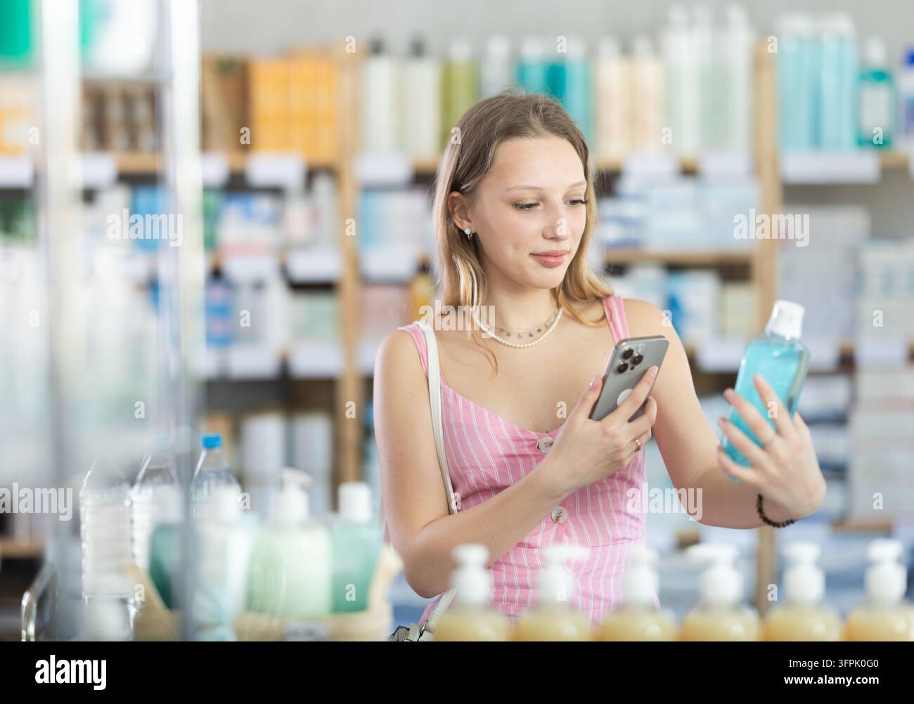 Ragazza in abiti estivi scansiona il codice su collutorio medicinale per controllare la data di scadenza Foto Stock