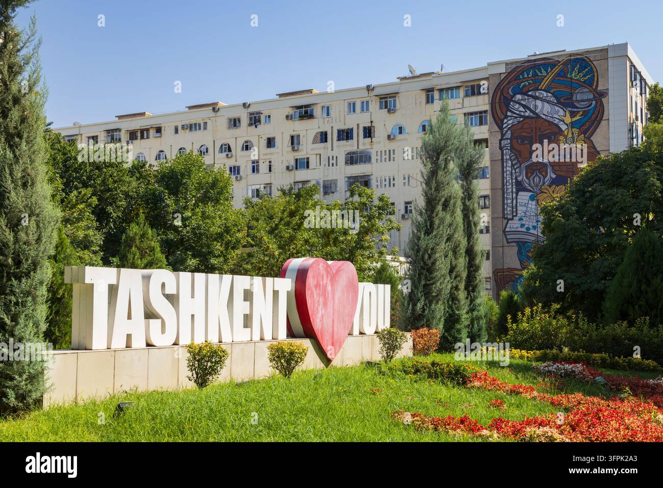 Un cartello "Tashkent ti ama" e un murale dell'astronomo uzbeko medievale Mirzo Ulugh Beg su un edificio residenziale dell'era sovietica. Tashkent, Uzbekistan Foto Stock