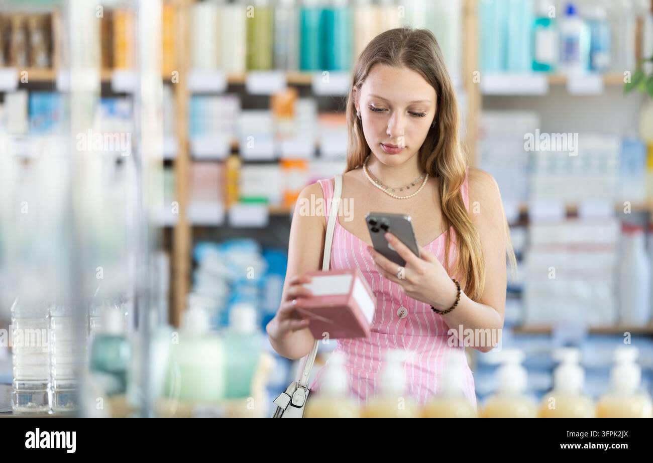 Ragazza in abiti estivi scansiona il codice sulla confezione di pillole per controllare la data di scadenza Foto Stock