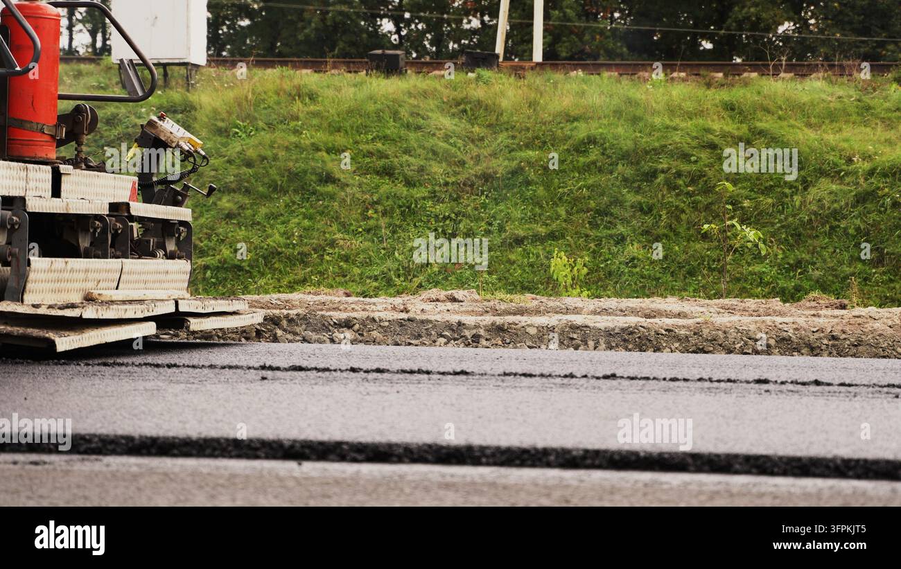 Posizione di nuovo asfalto in un cantiere stradale con una macchina da pavimentazione, infrastruttura di costruzione Foto Stock