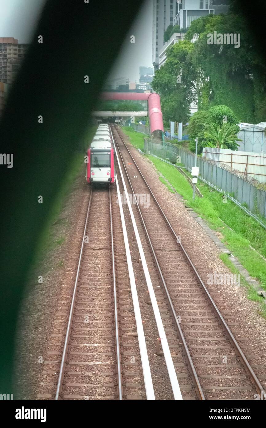 Un binario ferroviario con un treno in arrivo, vista da un ponte pedonale. Foto Stock