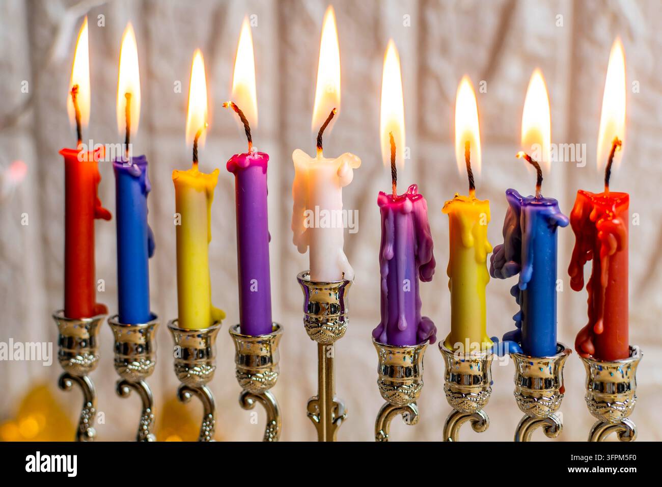Candele colorate in una menorah che bruciano luminose durante la celebrazione ebraica di Chanukkah Foto Stock