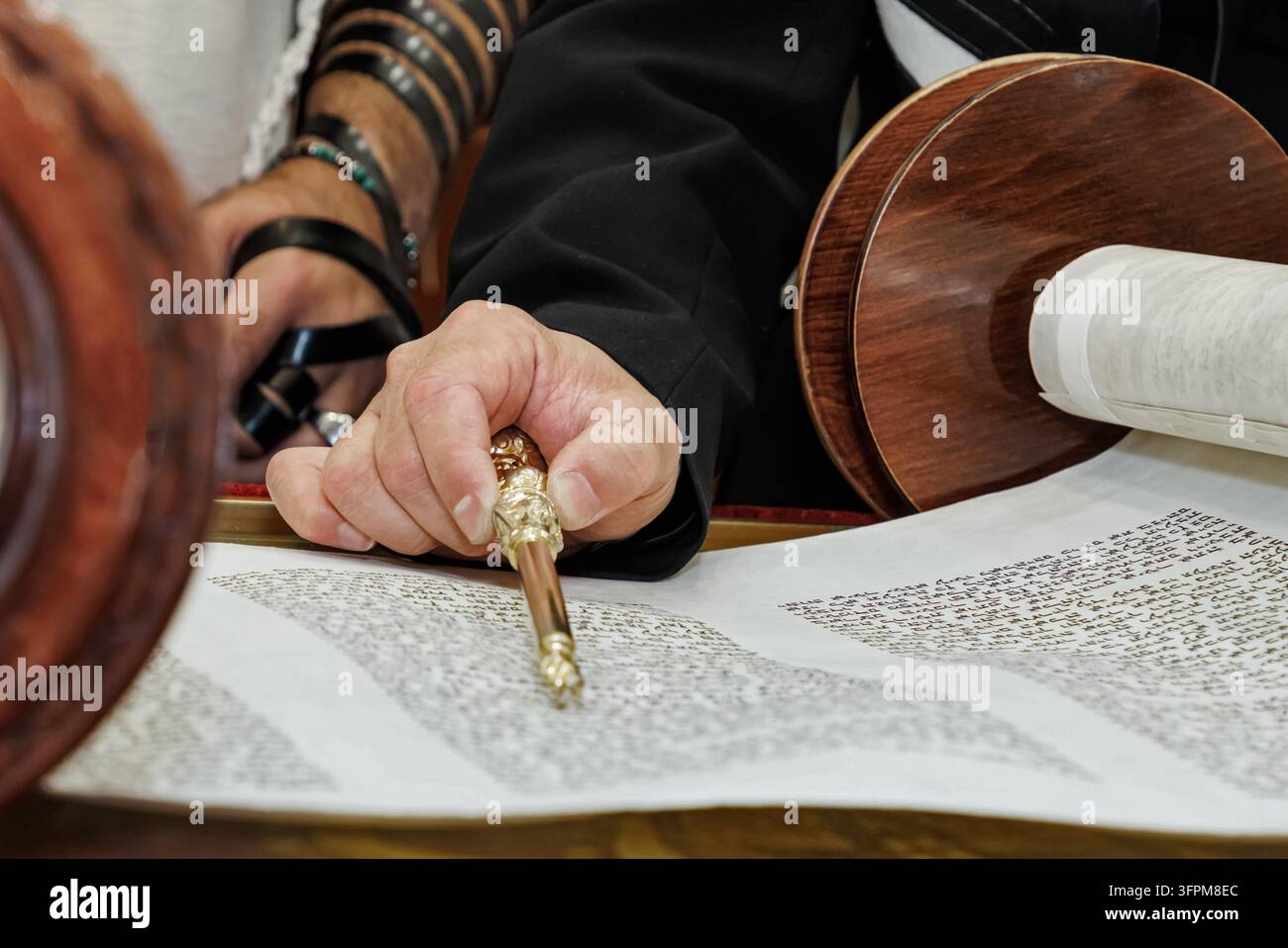 Prima piano della mano di un uomo che tiene un yad d'argento mentre legge da un rotolo della Torah. Foto Stock