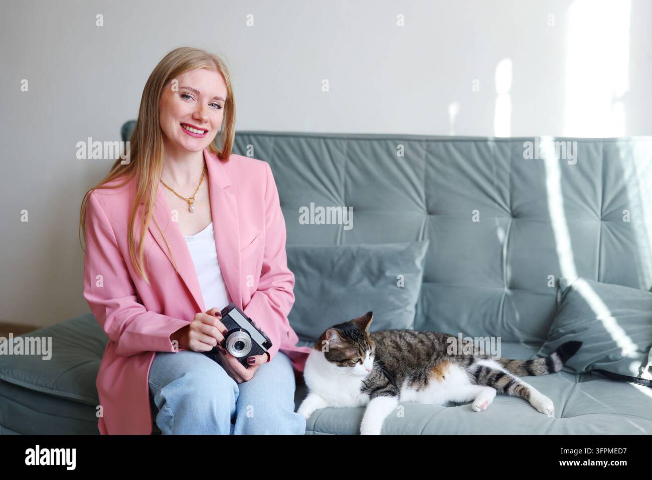 Creatore di contenuti con una fotocamera retrò e un gatto domestico, perfetto per i social media, la cura degli animali, lo stile di vita domestico e le campagne di branding personale. Foto Stock
