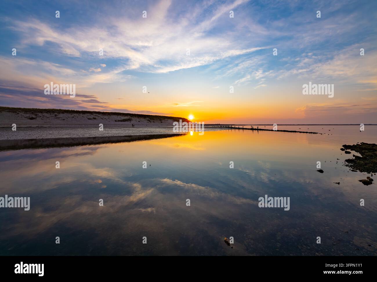 Tramonto dorato sulle valli di marea vicino a List su Sylt, con acque calme e poco profonde che riflettono il cielo colorato della sera durante la bassa marea. Foto Stock