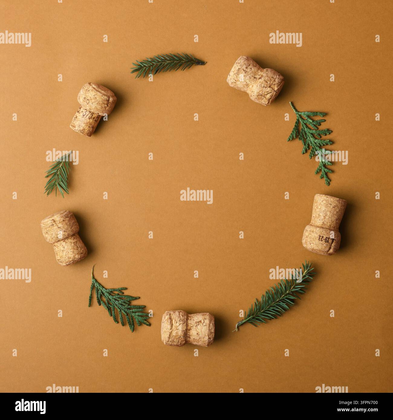 Ghirlanda natalizia creativa realizzata con tappi di champagne e rami di abete su uno sfondo marrone. Un layout concettuale che simboleggia lo spirito festivo e la natura Foto Stock